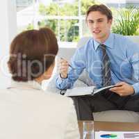 Young businessman scheduling with colleague sitting on couch