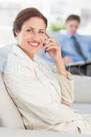 Cheerful businesswoman on the phone sitting on couch