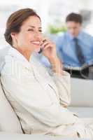 Cheerful businesswoman on the phone sitting on sofa