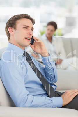 Cheerful businessman on the phone sitting on sofa