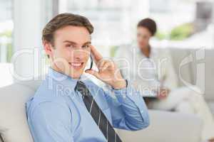 Smiling businessman on the phone sitting on couch