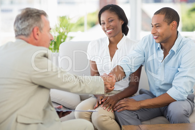 Young couple shaking hands with salesman on the couch