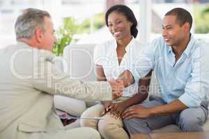 Young couple shaking hands with salesman on the couch