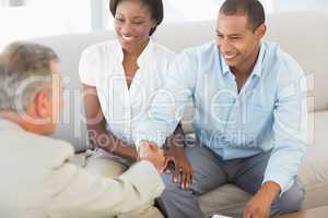 Young couple shaking hands with salesman on the sofa