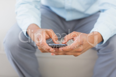 Man sending a text sitting on couch