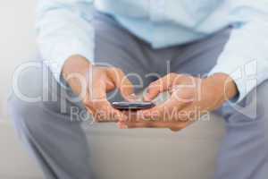 Man sending a text sitting on couch