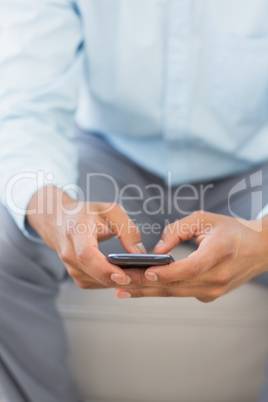 Man sending a text sitting on sofa