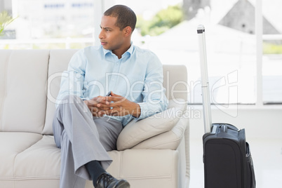 Businessman sitting on sofa waiting to depart on business trip