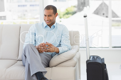 Happy businessman sitting on sofa waiting to depart on business