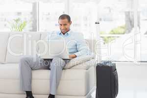 Happy businessman using laptop waiting to depart on business tri