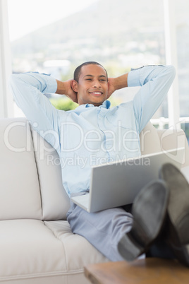 Relaxed smiling businessman on the couch with laptop