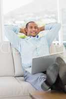 Relaxed smiling businessman on the couch with laptop