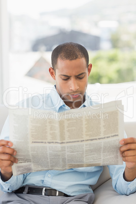 Serious businessman reading newspaper on the couch