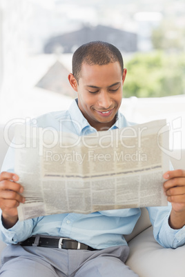 Smiling businessman reading newspaper on the couch