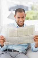 Happy businessman reading newspaper on the couch