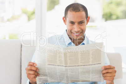 Smiling businessman reading newspaper on the couch