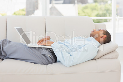 Businessman asleep on the couch with laptop