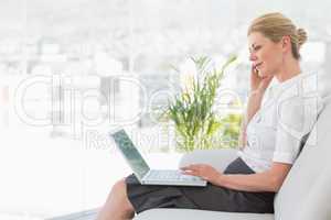 Businesswoman sitting on the sofa with laptop