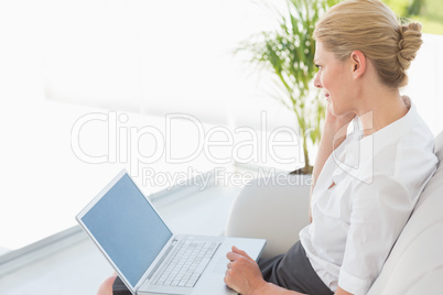 Businesswoman sitting on the couch working on laptop