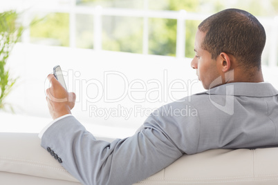 Businessman reading a text on the couch