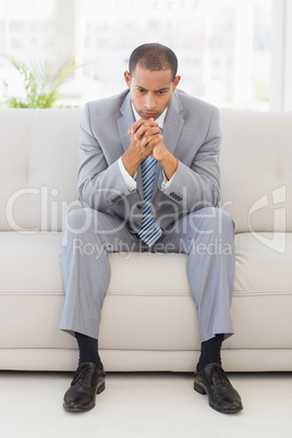 Anxious businessman sitting on couch