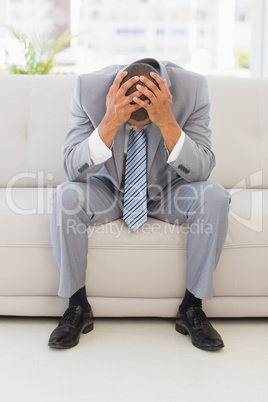 Stressed businessman sitting on couch