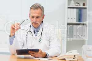 Focused doctor sitting at his desk with clipboard