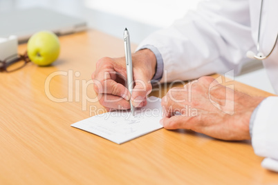 Doctor sitting at his desk writing out a prescription