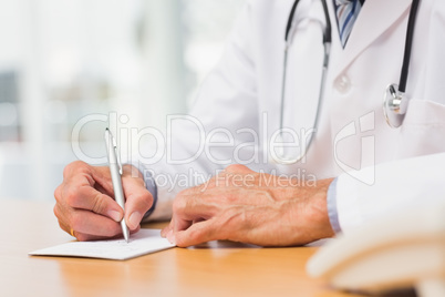 Doctor sitting at his desk writing a prescription