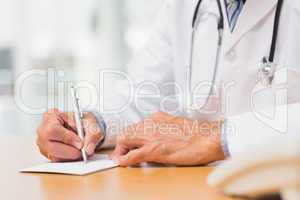 Doctor sitting at his desk writing a prescription