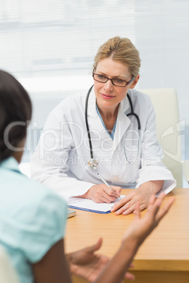 Concerned doctor listening to her patient and taking notes