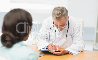 Doctor listening to his patient and taking notes