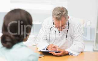 Doctor listening to his patient and taking notes