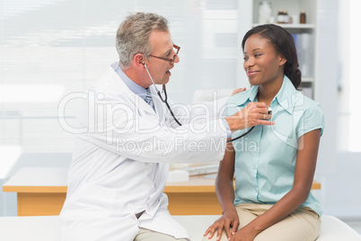 Doctor listening to cheerful patients chest with stethoscope