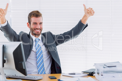 Cheerful businessman gesturing thumbs up at office desk