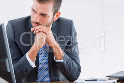 Young thoughtful businessman at office desk