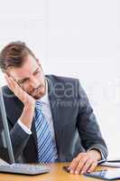 Thoughtful businessman sitting at office desk