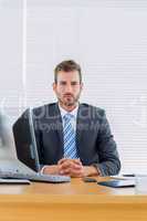 Serious businessman with computer at office desk
