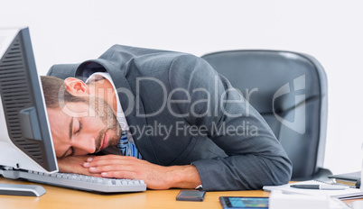 Businessman resting with head over keyboard at desk