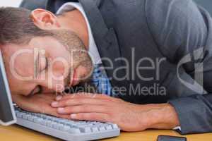 Businessman resting with head over keyboard at desk