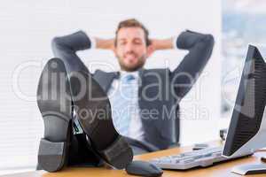 Relaxed businessman sitting with legs on desk at office