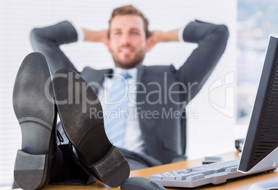 Relaxed businessman sitting with legs on desk