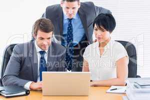 Colleagues using laptop at office desk