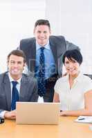 Smartly dressed colleagues with laptop at office desk