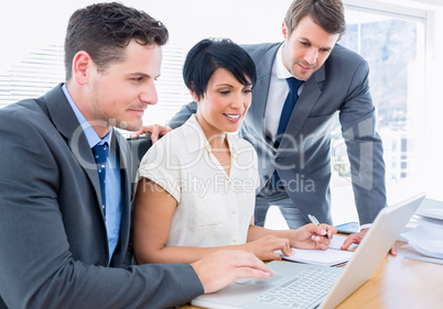 Young colleagues using laptop at office desk