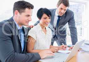 Young colleagues using laptop at office desk