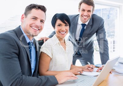 Young colleagues using laptop at office desk