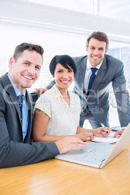 Colleagues using laptop at office desk