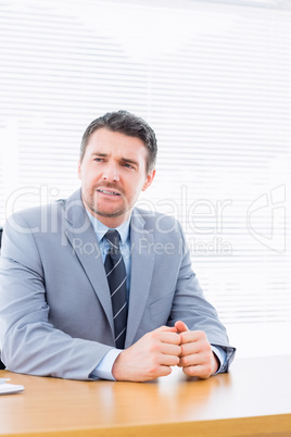 Thoughtful businessman in suit at office desk