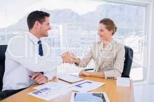 Smartly dressed colleagues shaking hands in a business meeting